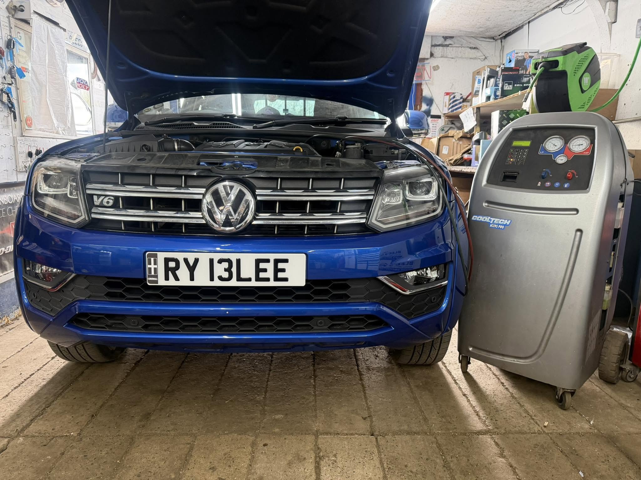A blue Volkswagen Amarok in the workshop, connected to the air conditioning machine