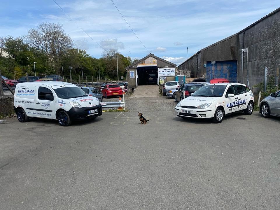 A Blee's Garage van and car in the yard, with the workshop behind