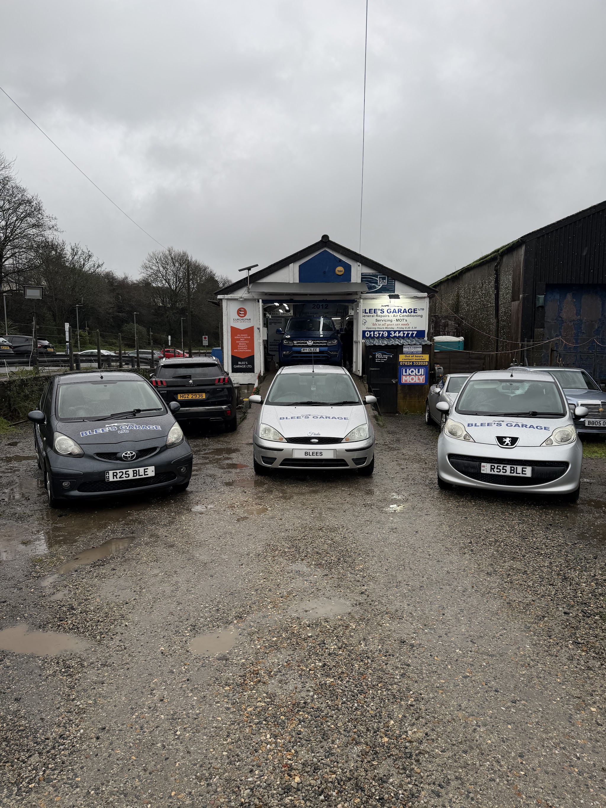 The yard at Blee's Garage with three Blee's Garage branded cars parked in front of the workshop
